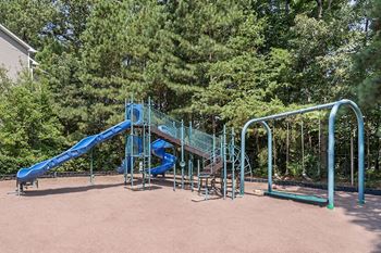 A playground with a blue slide and a green swing set.